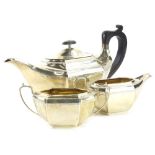 A George V silver three piece tea set, of elongated rectangular form with moulded bands, ebonised