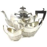 An Edwardian silver three piece tea set, of oval form with part fluted decoration, the teapot with