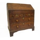 A George I oak bureau, with fall flap revealing a fitted interior of cupboard drawers and pigeon