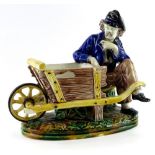 A Victorian majolica centrepiece, modelled in the form of a gardener with a rustic wheelbarrow, on