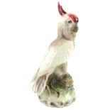 An Austrian pottery figure of a parakeet, with a red head on a naturalistic model base, 27cm H.