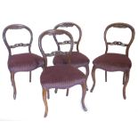 A set of four Victorian walnut balloon back chairs, each with a pierced and carved rail,