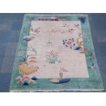 A 1930's chinoiserie style rug, decorated with a boat, lanterns and flowers, against a cream ground,