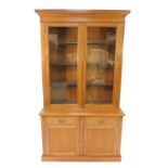 A Victorian oak cupboard bookcase, the outswept pediment over two doors, enclosing three shelves,