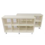 A pair of white MDF eight section open bookcase/display cabinets, raised on cylindrical white