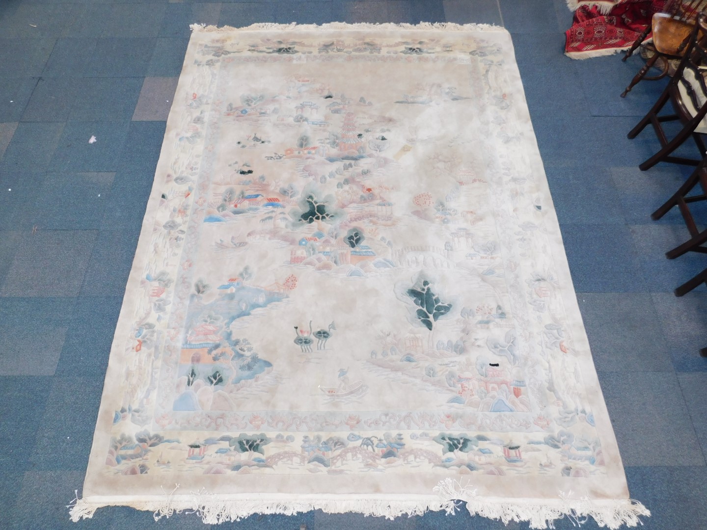 A Chinese rug decorated with a landscape, against a cream ground, 384cm x 275cm.