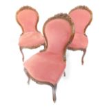 A set of three Victorian walnut balloon back salon chairs, with a rose carved crest rail, red
