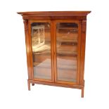 A Victorian mahogany bookcase, on a later stand, the outswept pediment over a pair of glazed