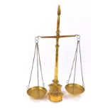 A pair of Victorian brass beam scales, raised on a turned column and shaped base, holding eight