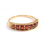 A 9ct gold and garnet seven stone half hoop ring, size O, 2.5g.