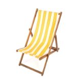 A vintage deck chair, upholstered in white and yellow striped fabric.