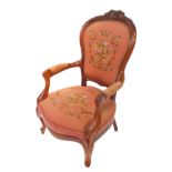 A Victorian mahogany lady's spoon back armchair, with foliate carved crest rail, wool work floral