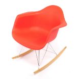 A Charles Eames design RAR retro rocking armchair, having a formed red plastic seat, chromed wire