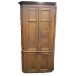 A George III oak standing corner cupboard, with moulded cornice, over two double moulded panel doors