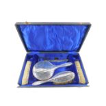 A George V silver five piece dressing table set, each piece engraved with fleur de lys and bearing