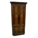 A George III oak freestanding corner cupboard, having Greek key carved and moulded cornice, over two