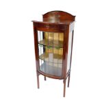 A Victorian mahogany bow front display cabinet, with a carved and dome pediment back, over a lead