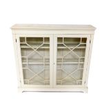 A Maple & Company early 20thC bookcase, later cream painted, the outswept cornice, over two astragal