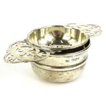 An Elizabeth II silver tea strainer and stand, with two handles pierced with leaves etc.,