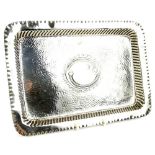 An Edwardian silver rectangular dressing table tray, with raised border, hammered interior,