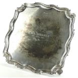 A George V silver salver by Walker and Hall, with piecrust edge on quadruple scroll supports,