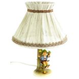 A Goebel Hummel ceramic lamp base, modelled in the form of a boy seated on a fruit tree branch