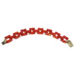 An early 20thC coral bracelet, with carved coral links in three row spaced design, with yellow metal