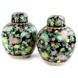 A pair of Chinese famille noire ginger jars, each decorated with brightly coloured flowers, in pink,