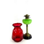 A late Victorian brass oil lamp, with associated ruby tinted shade, the green glass reservoir