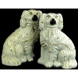 A pair of 19thC Staffordshire pottery spaniels, each with gilt coloured mounts, the eyes picked