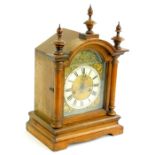 A late 19thC German mantel clock, in a walnut case, the arched dial applied with gilt metal embossed