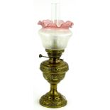 An early 20thC brass oil lamp, with clear funnel, frosted pink glass and shade, inverted stem and