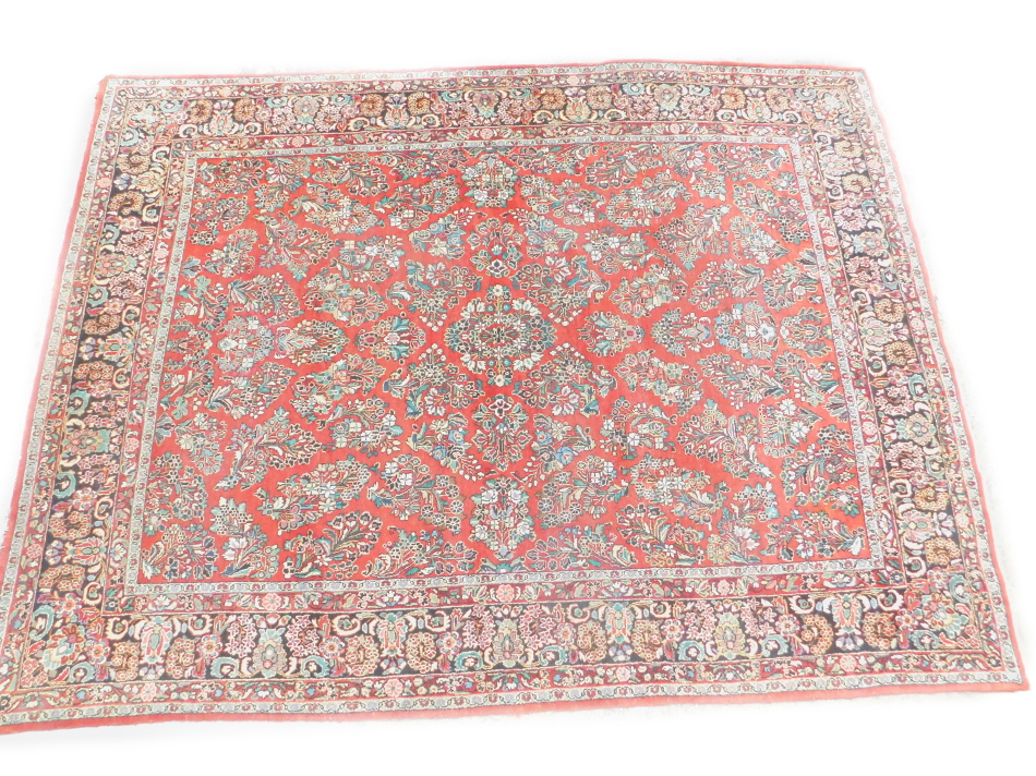A Persian Meshed type carpet, with a design of flowers on a red ground with multiple borders,