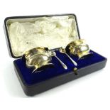 A George V silver open salt set, comprising two bombe shaped salts with repousse decorated leaf