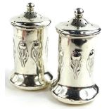 A pair of early 20thC silver pepper pots, each decorated with tulips in Art Nouveau style, on a