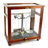 An Oertling set of laboratory scales, in aluminium and brass, in a glazed mahogany case, 49cm H,