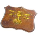 An early 20thC mahogany plaque, decorated with a transfer print of a gilt bi plane and the crest