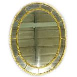 An oval gilt wall mirror, with central plate, surrounded by smaller plates, within beaded and