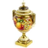 A Royal Worcester porcelain two handled urn and cover, painted with fruit by Paul English, the lid