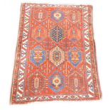 A Persian rug, with a design of twelve multi coloured medallions on a red ground with one wide