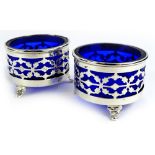 A pair of George V silver cylindrical salts, each with pierced decoration, blue glass liner and