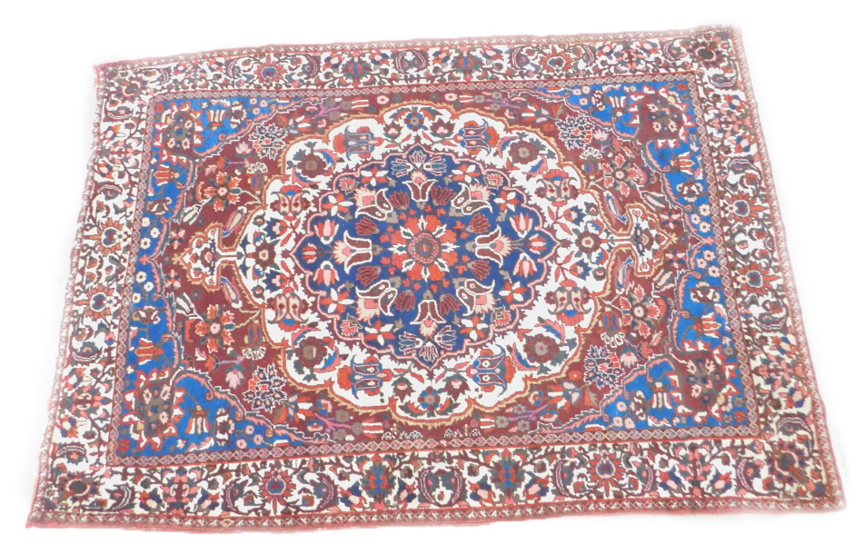 A Persian carpet, with an all over design of flowers, on a red ground with multiple borders, 314cm x