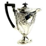 An early 20thC silver coffee pot, with ebonised knop and handle, embossed overall with flowers etc.,