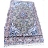 A Kashmir wool rug, with a central medallion surrounded by leaves, trees etc., on pale ground with