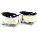 A pair of George V silver salts, of oval form on quadruple hairy paw feet, with blue glass liners,