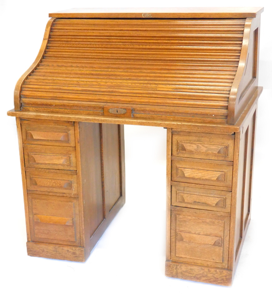 An early 20thC oak roll top desk, the tambour front enclosing a fitted interior above four drawers