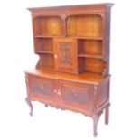 An early 20thC carved oak dresser, the raised plate rack with a central carved panel door, decorated