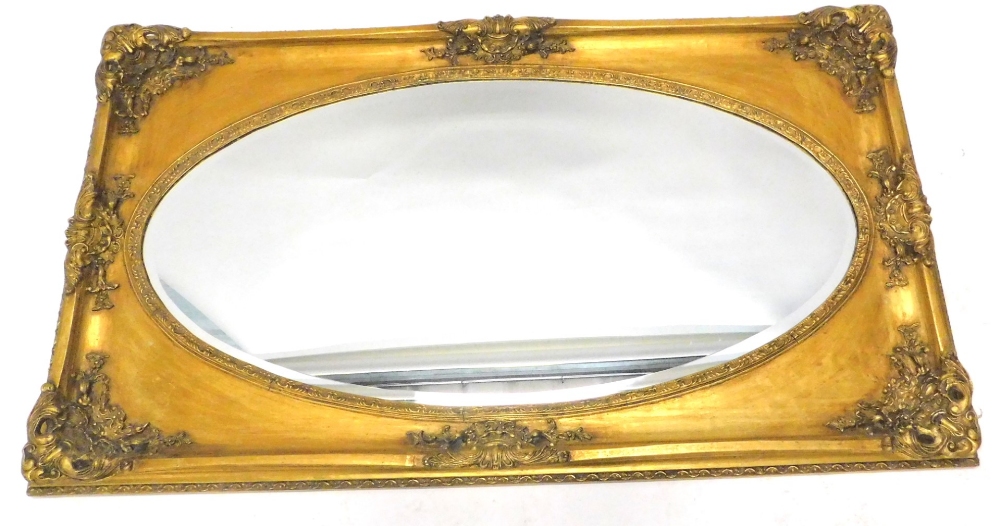 A gilt rectangular wall mirror, with an oval bevel plate, 75cm x 150cm.