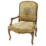 A late 19th/early 20thC Continental walnut open armchair, upholstered in woolwork tapestry type