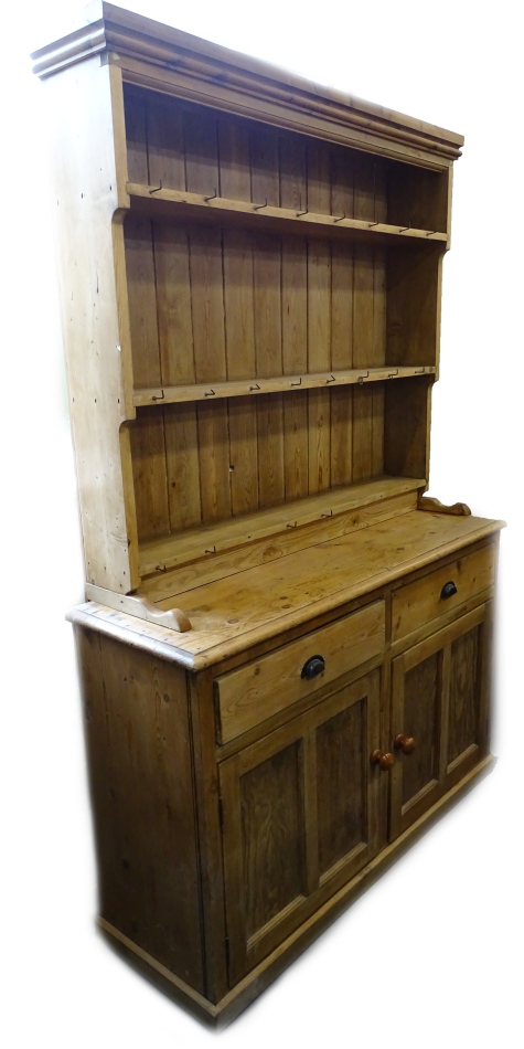 A 19thC and later pine dresser, the plate rack with three shelves, the base with two drawers and two